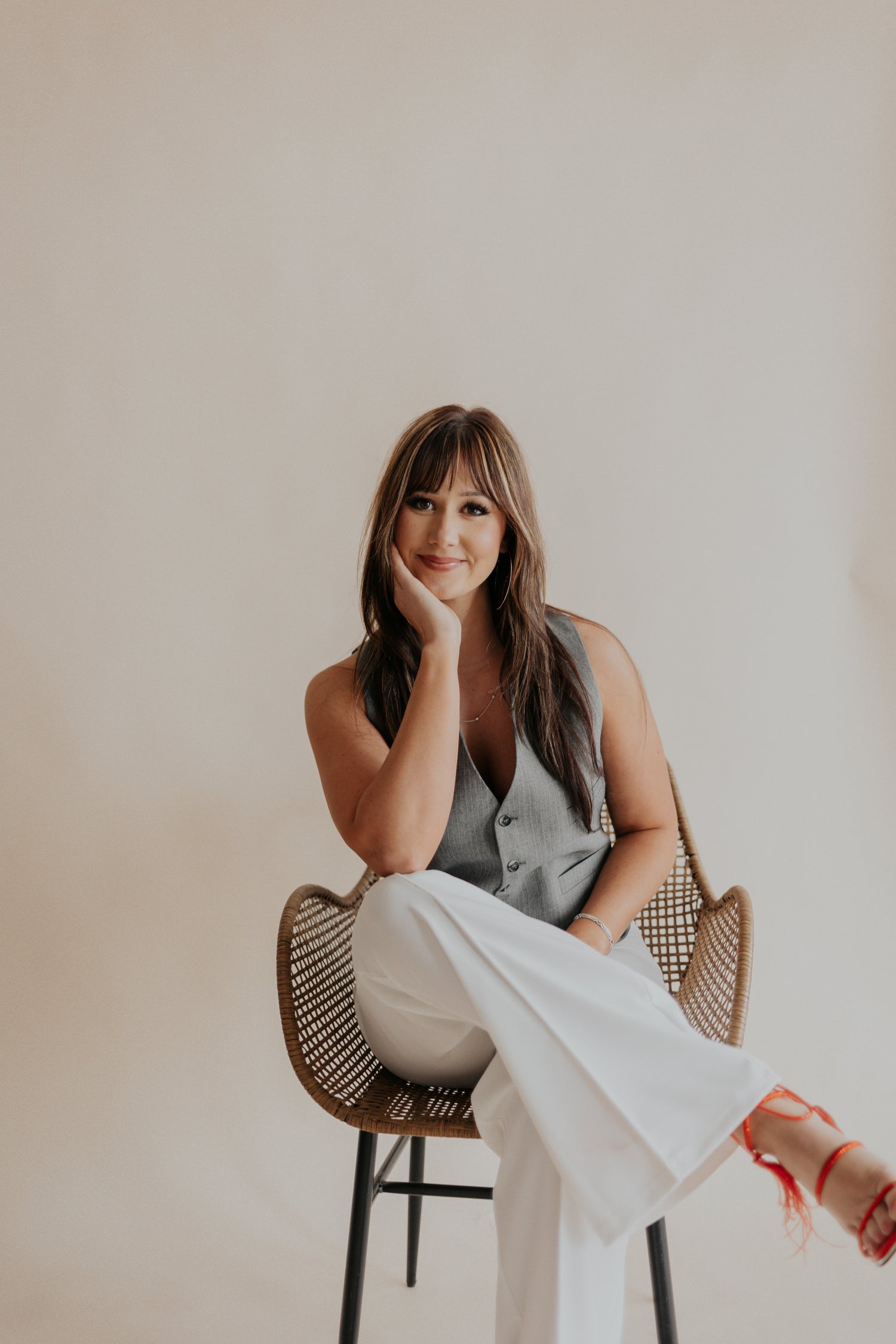 Woman sitting on a chair with a neutral background, lash extension artist Lauren and business woman
